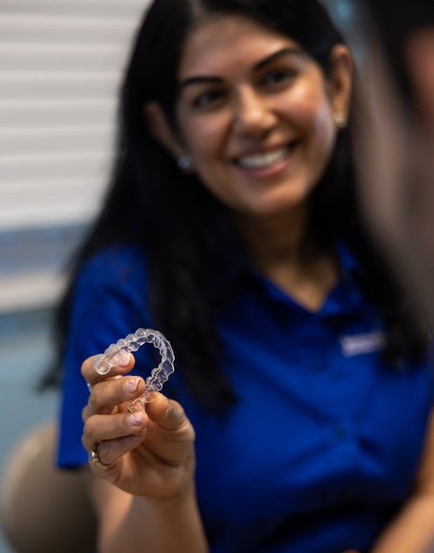 Dr. Dham holding a clear Invisalign aligner